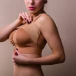 Young woman wearing a compressing bra after a breast enhancement surgery