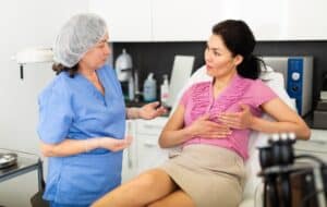 Adult woman consulting with an experienced cosmetologist about breast lift and reshaping procedures, exploring options for enhanced contour and firmness.