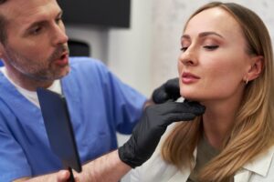 A woman sits in a cosmetic surgery clinic before her facelift procedure to discuss facial rejuvenation options