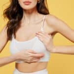 Cropped image of young woman in white underwear touching chest, concept of breast symmetry, health, and beauty care