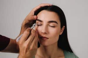 Doctor marking patient’s upper eyelids with medical pen for blepharoplasty, concept of precise planning for eyelid lift surgery